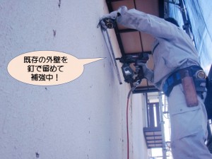 既存の外壁を釘で留めて補強中