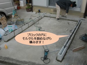 ブロックの穴にモルタルを詰めながら積みます